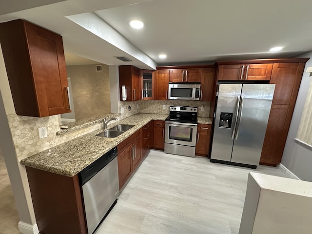 2201 Lucaya Bnd Unit M1, Coconut Creek, FL 33066 - kitchen featuring a sink, appliances with stainless steel finishes, backsplash, and light stone counters