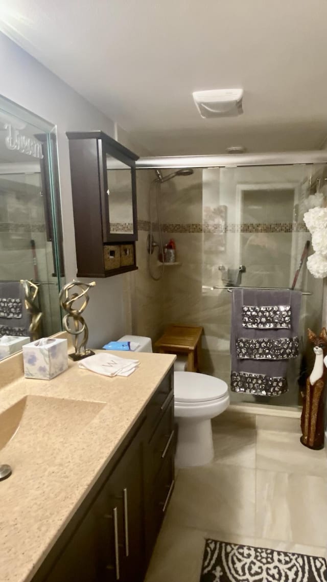 bathroom with tile patterned floors, toilet, vanity, and an enclosed shower