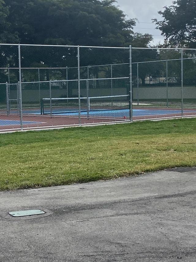 view of tennis court with a yard