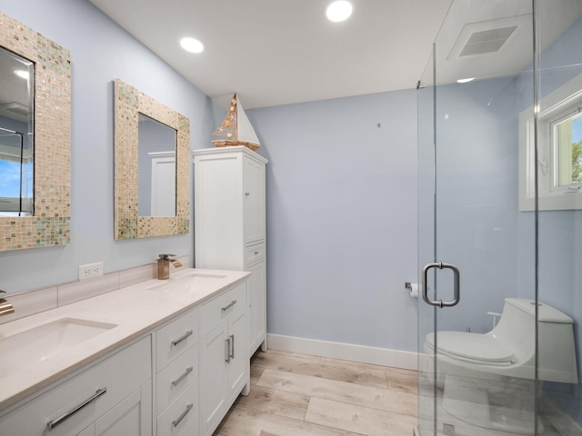 bathroom featuring vanity, hardwood / wood-style flooring, a shower with door, and toilet