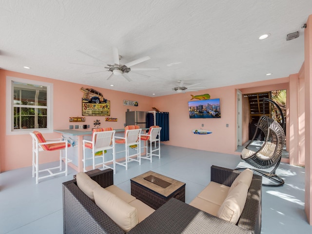 living room featuring ceiling fan and a textured ceiling