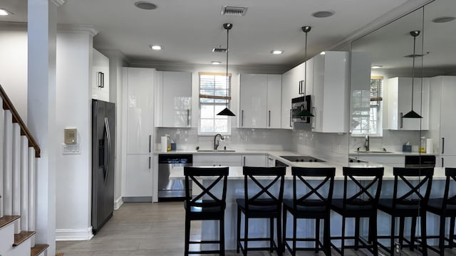 kitchen featuring visible vents, hanging light fixtures, stainless steel dishwasher, white cabinetry, and refrigerator with ice dispenser