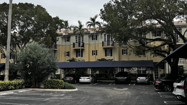 view of building exterior with covered and uncovered parking