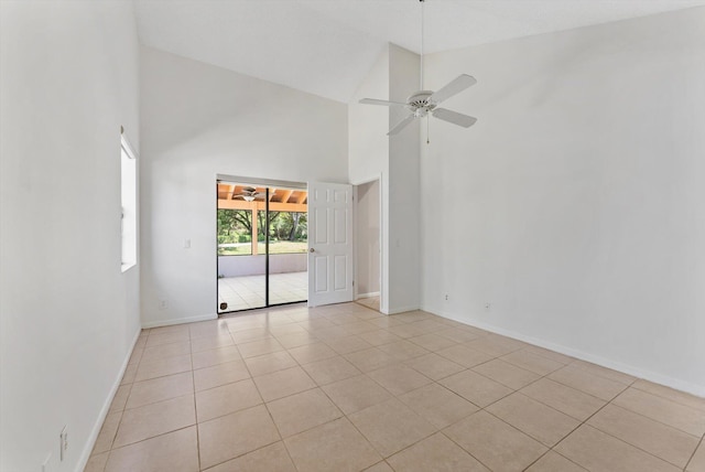 spare room with baseboards, high vaulted ceiling, light tile patterned floors, and a ceiling fan