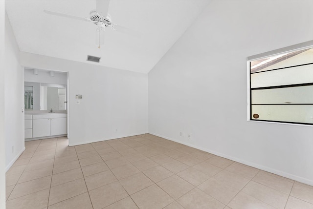 spare room featuring light tile patterned floors, visible vents, vaulted ceiling, and a ceiling fan