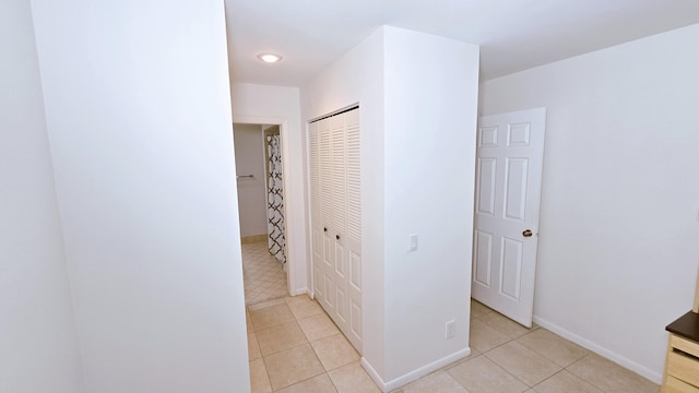 corridor with light tile patterned flooring and baseboards