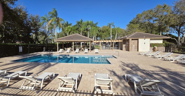 community pool with a patio area, a gazebo, and fence