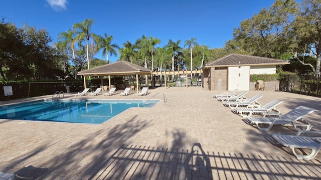 community pool with a patio, fence, and a gazebo