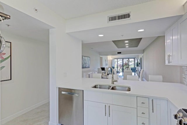 kitchen featuring sink, stainless steel dishwasher, white cabinets, and kitchen peninsula