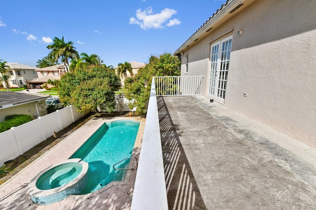 view of pool featuring a pool with connected hot tub, a patio area, a residential view, a fenced backyard, and french doors