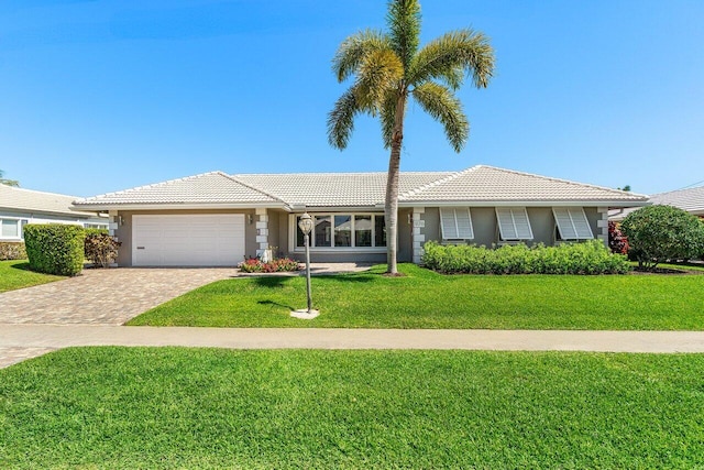 ranch-style home featuring a front lawn, an attached garage, a tile roof, and stucco siding