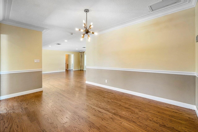 empty room featuring crown molding, wood finished floors, baseboards, and a chandelier