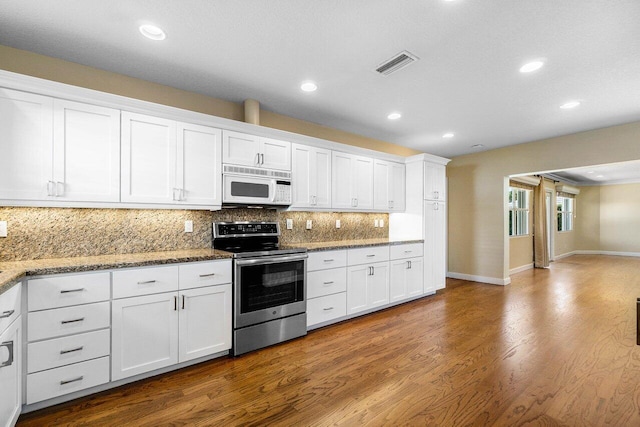 kitchen featuring white microwave, visible vents, dark wood finished floors, stainless steel electric stove, and white cabinetry