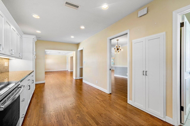 kitchen featuring electric range, visible vents, wood finished floors, white cabinetry, and a chandelier