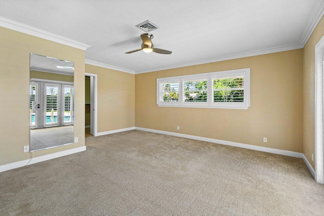 carpeted spare room with visible vents, a ceiling fan, a textured ceiling, crown molding, and baseboards