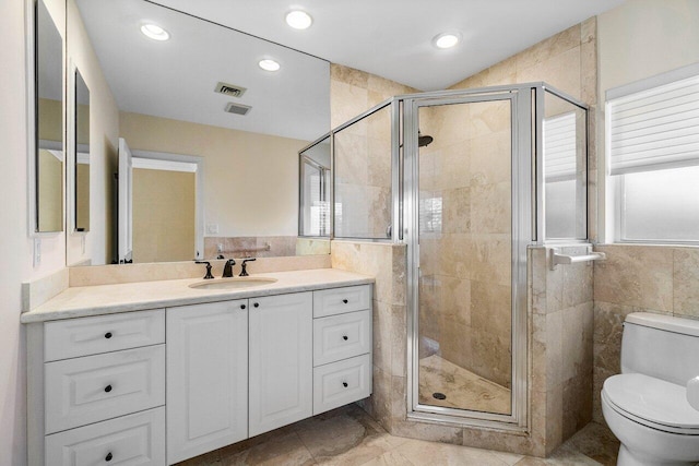 bathroom featuring tile walls, toilet, visible vents, and a stall shower