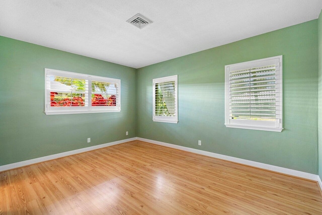 spare room with visible vents, light wood-style flooring, and baseboards