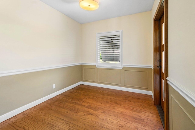 empty room with wainscoting and wood finished floors