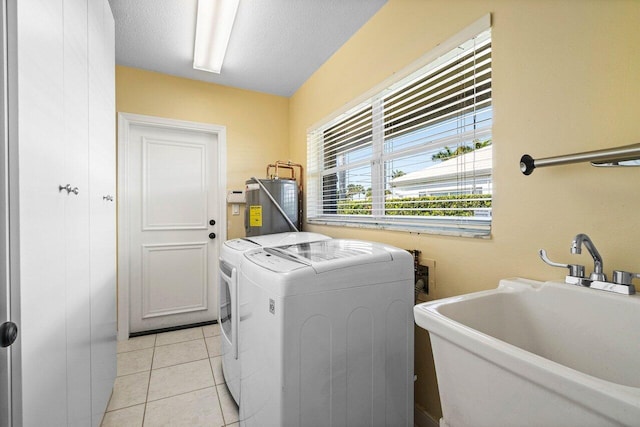 laundry area with washer and clothes dryer, water heater, laundry area, light tile patterned floors, and a sink