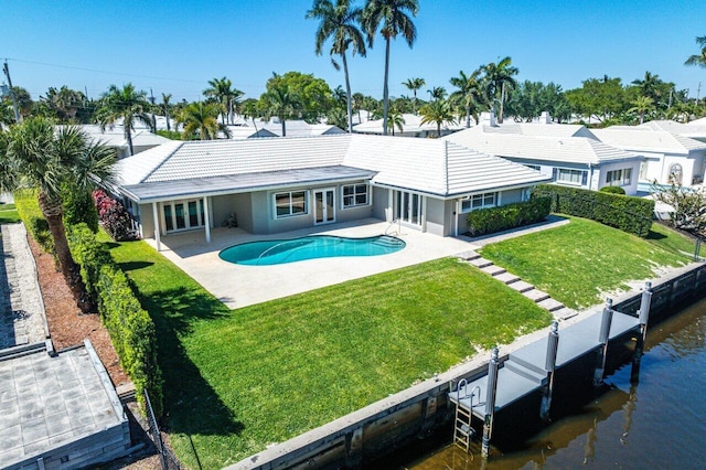 back of property featuring a lawn, a tile roof, fence, an outdoor pool, and a patio area