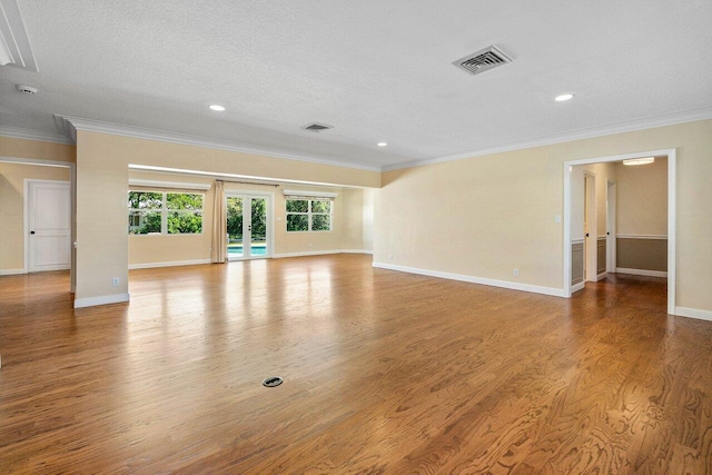 unfurnished living room featuring visible vents, french doors, crown molding, and wood finished floors