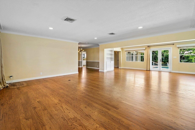 unfurnished living room with wood finished floors, visible vents, baseboards, crown molding, and a notable chandelier