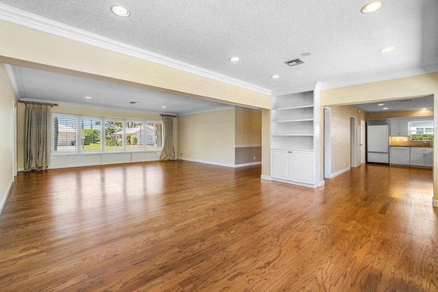 unfurnished living room with a wealth of natural light, visible vents, a textured ceiling, and wood finished floors