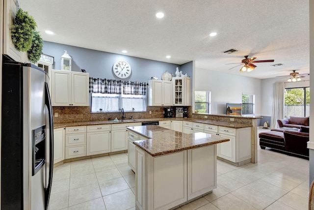 kitchen featuring a kitchen island, stone countertops, stainless steel fridge with ice dispenser, decorative backsplash, and kitchen peninsula