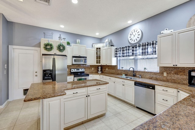 kitchen with sink, stainless steel appliances, a center island, light stone counters, and white cabinets