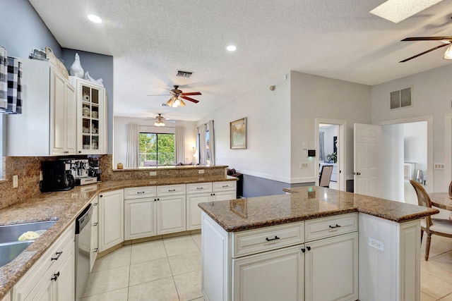 kitchen featuring stone countertops, light tile patterned floors, a kitchen island, and white cabinets