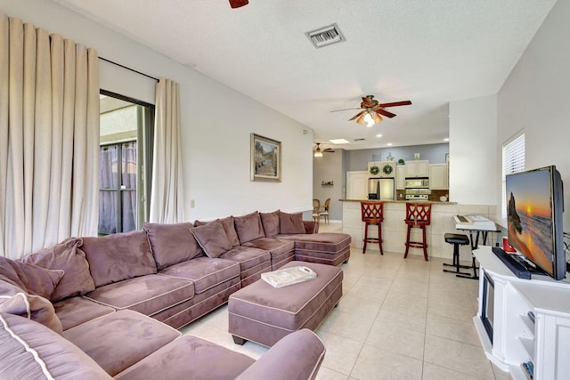 living room featuring light tile patterned floors, a textured ceiling, and ceiling fan