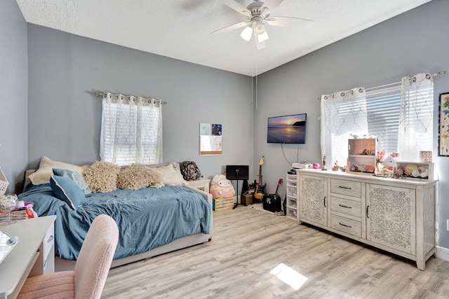 bedroom featuring vaulted ceiling, ceiling fan, light hardwood / wood-style floors, and a textured ceiling