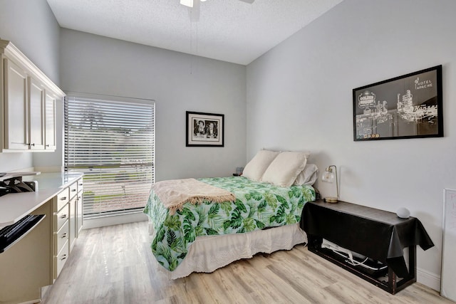 bedroom featuring ceiling fan, a textured ceiling, and light wood-type flooring