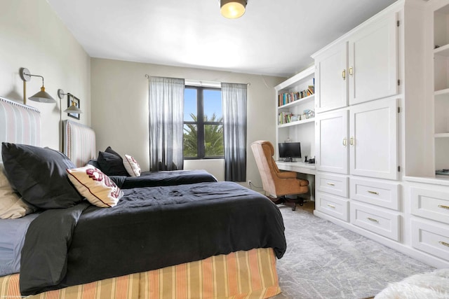 bedroom with built in study area and light colored carpet