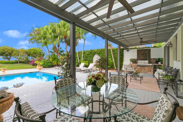 view of patio featuring outdoor dining area, exterior kitchen, grilling area, a fenced in pool, and a pergola