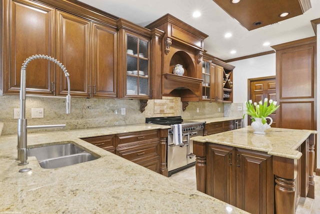 kitchen with tasteful backsplash, glass insert cabinets, light stone countertops, double oven range, and a sink