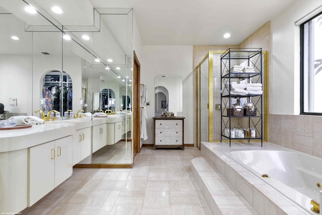 bathroom with a stall shower, baseboards, vanity, a bath, and recessed lighting