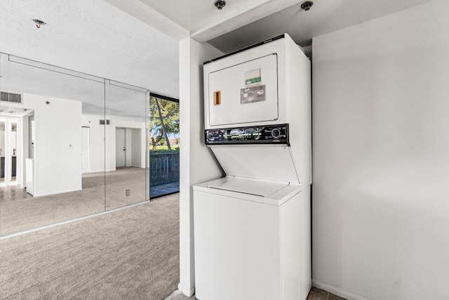 laundry room featuring carpet, stacked washer / drying machine, and a textured ceiling