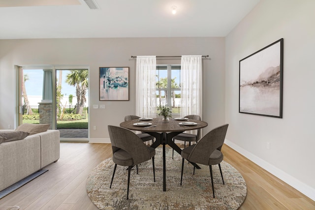 dining space with light wood finished floors, visible vents, and baseboards