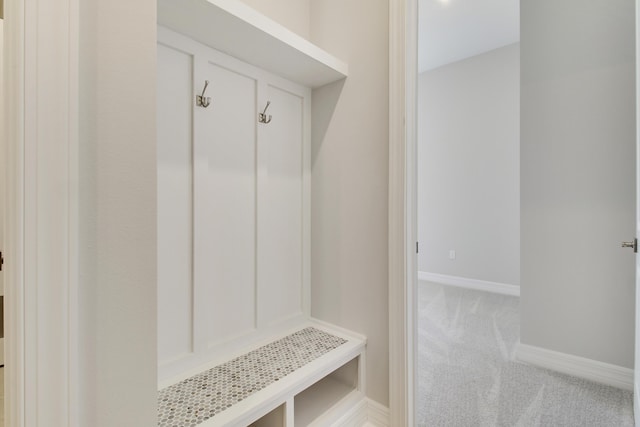 mudroom with baseboards and light colored carpet