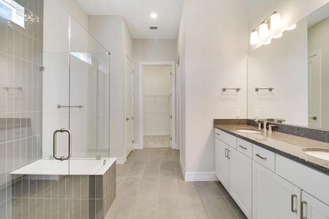 bathroom with visible vents, tile patterned flooring, a walk in closet, a shower stall, and a sink