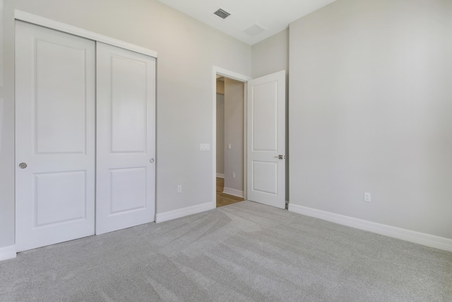 unfurnished bedroom with a closet, visible vents, light carpet, and baseboards