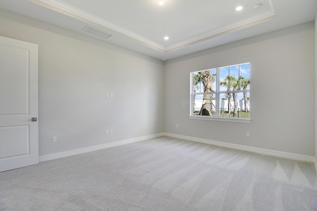 empty room with a tray ceiling, light colored carpet, and baseboards