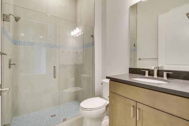 bathroom with toilet, a shower stall, and vanity