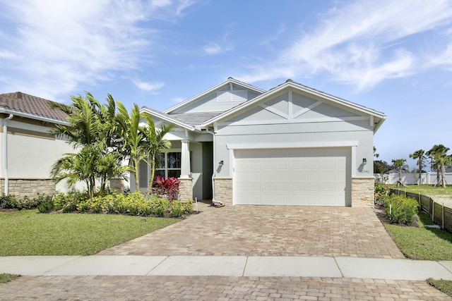 craftsman-style house featuring a garage, stone siding, and decorative driveway