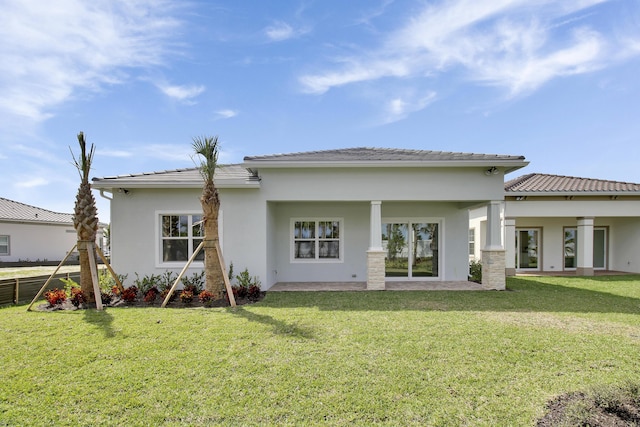 rear view of property with stucco siding, a tiled roof, and a yard