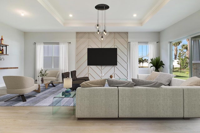 living area with a tray ceiling, crown molding, light wood finished floors, and recessed lighting