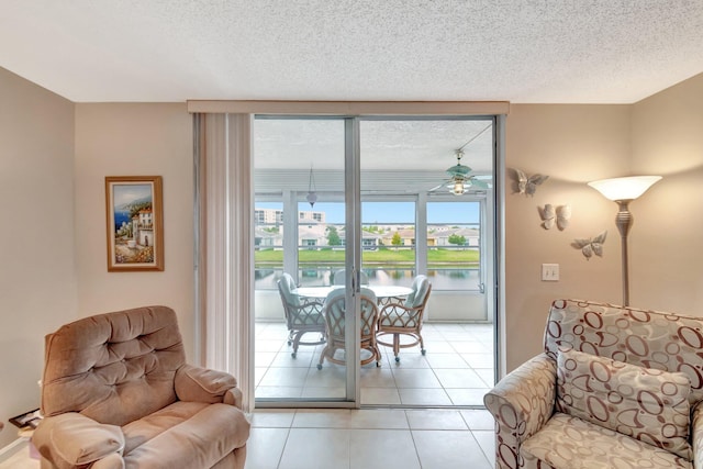 sitting room with light tile patterned floors, a textured ceiling, and a water view