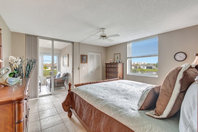 bedroom with a ceiling fan, access to outside, a textured ceiling, and light tile patterned floors