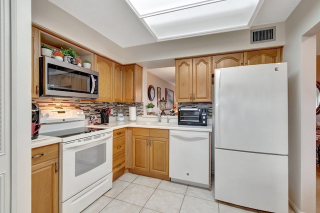 kitchen featuring light tile patterned floors, white appliances, a sink, visible vents, and light countertops